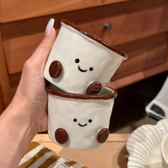 新しいカカオ豆の手はコップを握ってかわいいきれいなお茶のコップを飲みます。