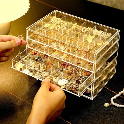 A transparent jewelry box with compartments for earrings, necklaces, rings, and beads