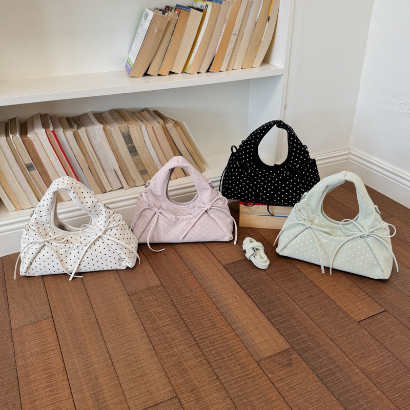 Bolsa de mano de arco exquisita coreana para mujeres verano 2026 simple diaria versátil onda punto sensación de hombro mochila