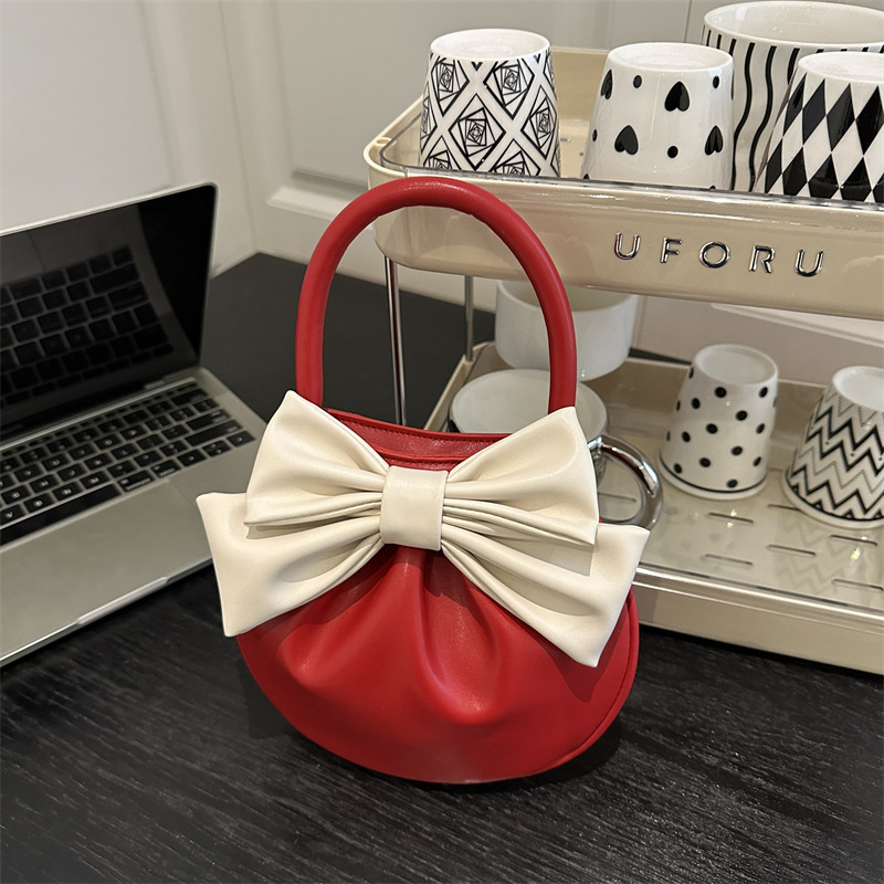 2025 primavera y verano nuevo nicho de diseño de arco bolsos portátiles de mujer alta sensación pequeña bolsa redonda roja