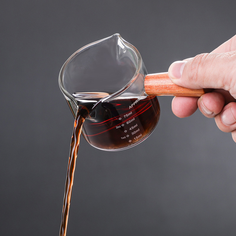 側木は口の小さいミルクの杯の透明なガラスを目盛りの測定の杯のエスプレッソのオンスの杯の小さいミルクの缶を持ちます。|undefined