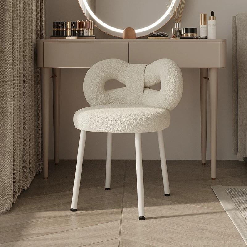 Trendy, cream-colored designer vanity chair with a luxurious, high-end feel, featuring a bow and lamb wool upholstery, perfect for a bedroom dressing table