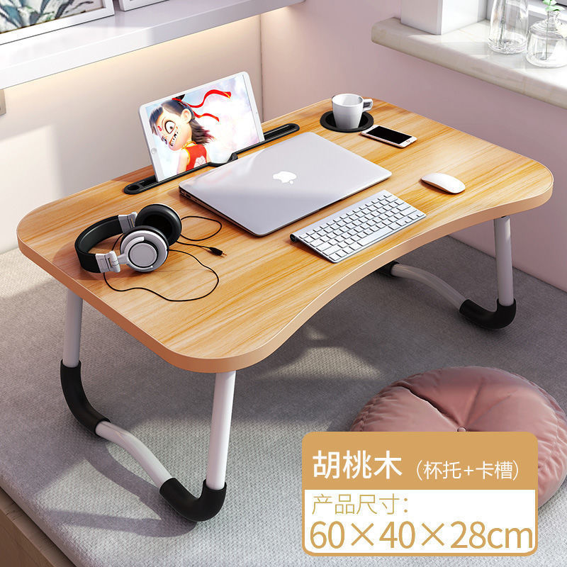 ベッドの上の机の折り畳みの小さい机は引き出しを持っています。|undefined