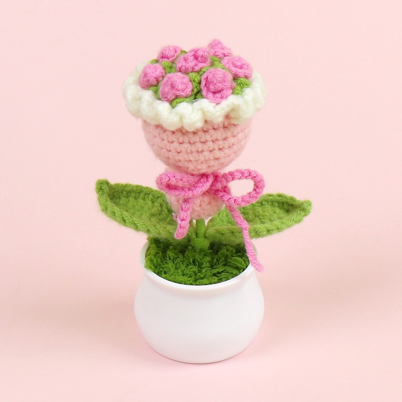 Maceta rosa con flores en la mano