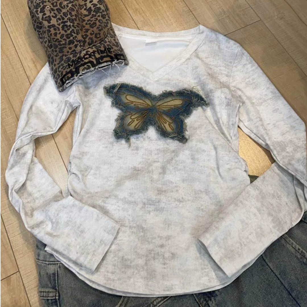 Ранняя весенняя бабочка красит футболку с длинными рукавами на плече