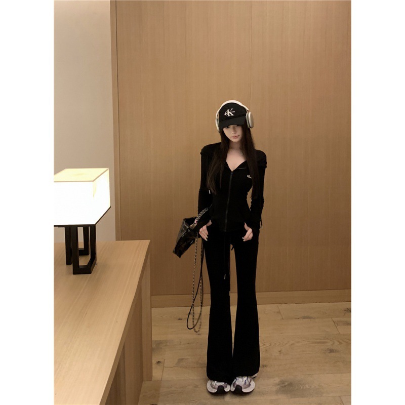 カジュアルスポーツスーツの女性は秋に帽子をかぶって腰のガードルのコートを着て、スピーカーでズボンを2セット持っています|undefined