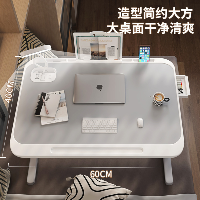 ベッドの上でコンピュータの机の寮を畳んで電気スタンドを勉強します。|undefined