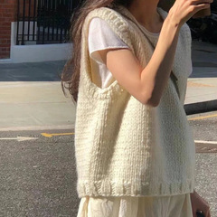 柔らかいモチのレトロな白いニットのベストの女性は秋冬に肩のセーターのベストを重ねて着ます。