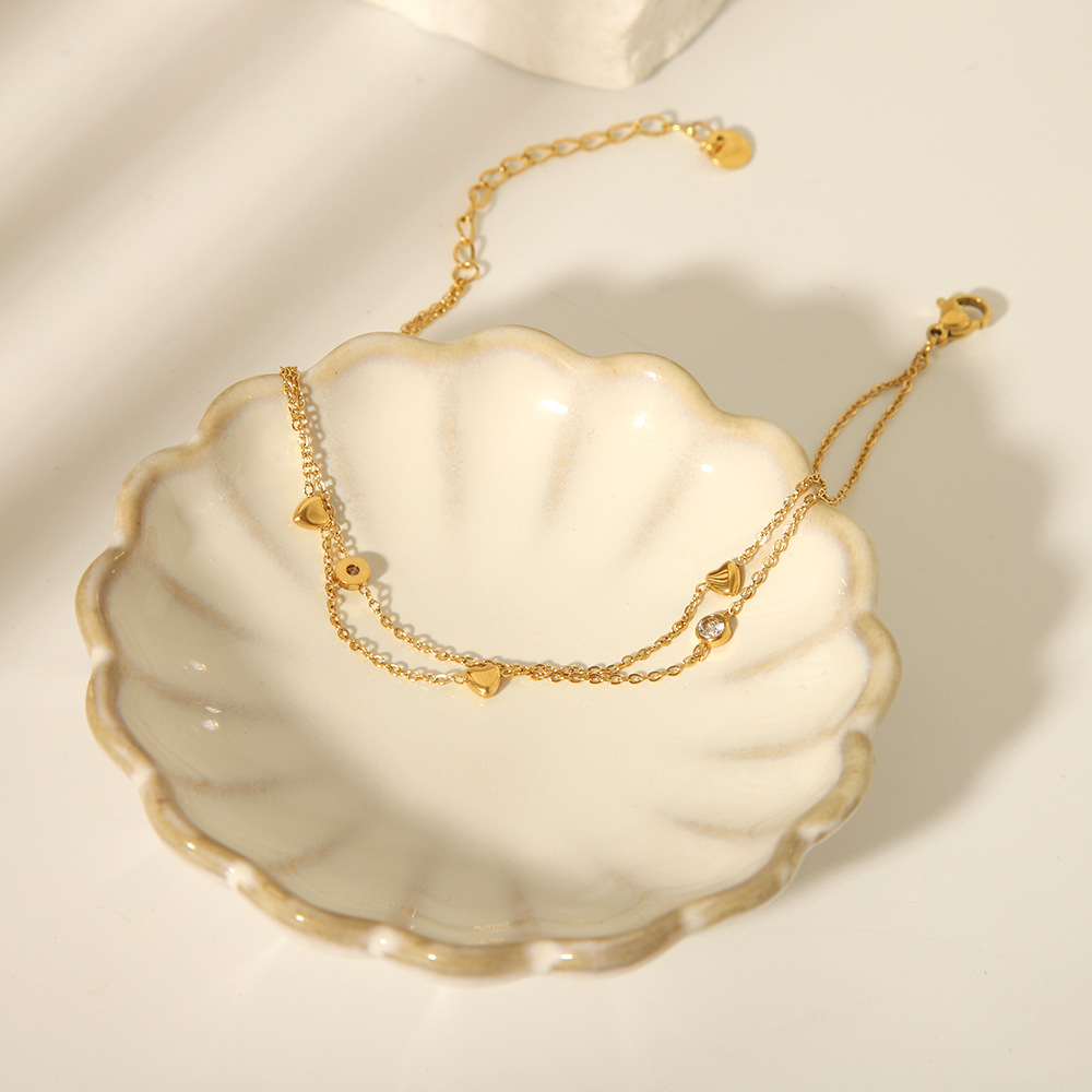 Estilo francés acero de titanio horno de 18K galvanoplastia de oro real doble amor circón tobillera verano femenino todo fósforo joyería de playa