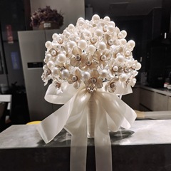 新婦の手で花を持つdiy材料は真珠の貝殻を包んで、新しいものを送って、結婚式のプレゼントを手作りします。
