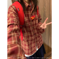 気質のレトロな赤い格子の長袖のシャツの女性の中に重ねてゆったりしています。