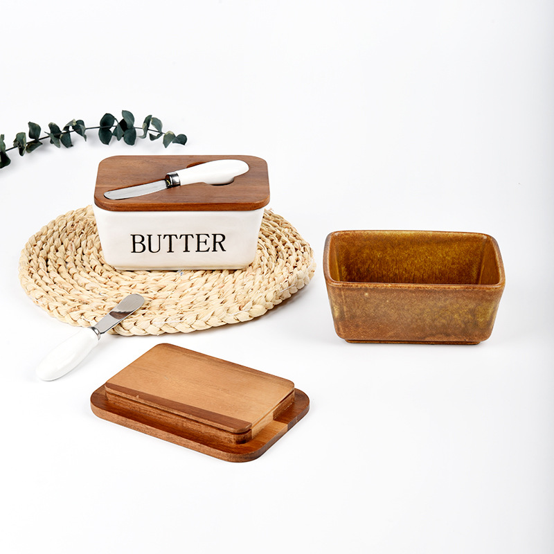 Mantequillera de cerámica con tapa de madera y cuchillo, apta para uso alimentario.