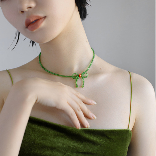 A minimalist and stylish green butterfly knot necklace for women, featuring small, fresh and elegant glass crystal beads, designed as a choker or lockchain.