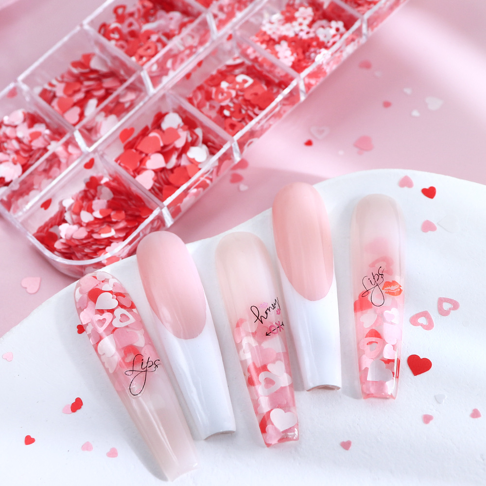 Caja de 12 compartimentos con accesorios perlados para decoración de uñas en forma de corazón, lentejuelas para uñas con diseño de mariposas y flores en rosa y blanco para el Día de San Valentín, decoraciones coloridas.