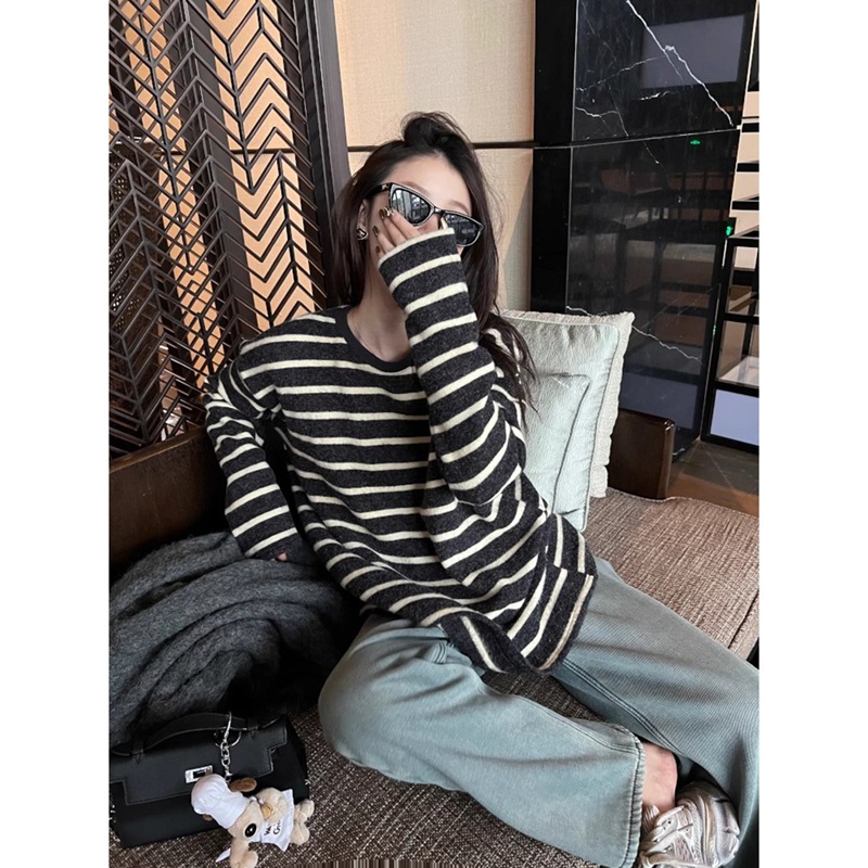 怠惰でゆったりしていて、やせている長袖のストライプのtシャツの女性の百合