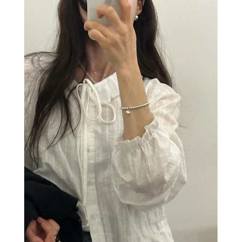White long-sleeved shirt with floral lace and ribbon details, featuring a sweet chic early autumn vibe, paired with a knitted cabled vest.
