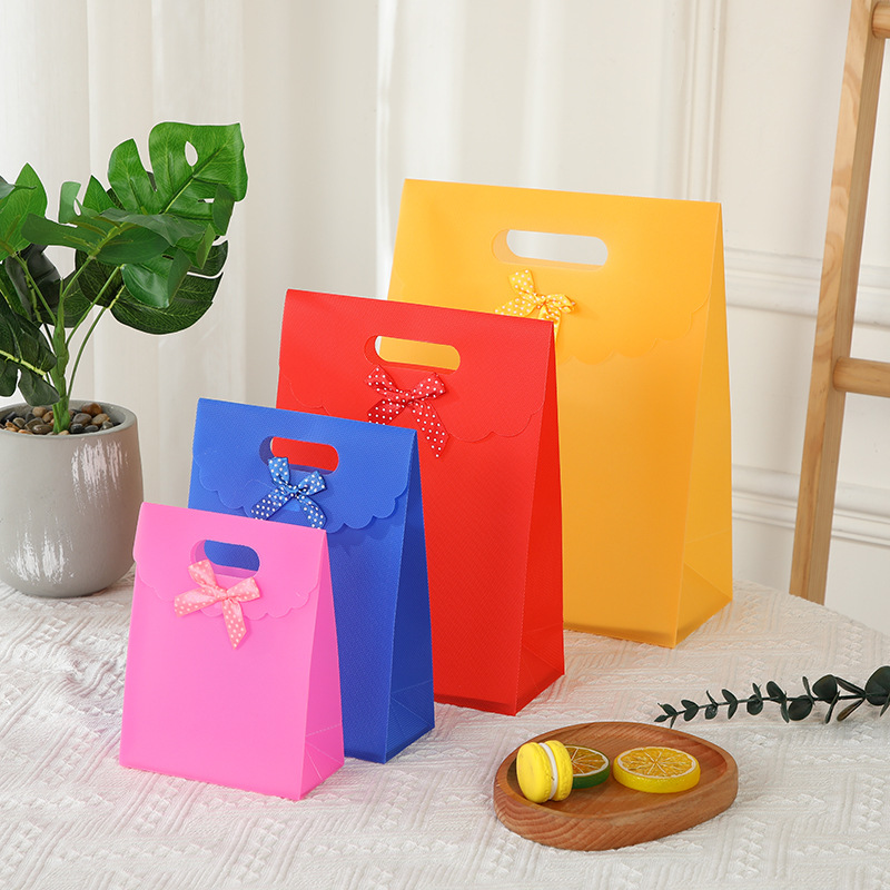 Bolsa de regalo con lazo multicolor, bolsa de mano de polipropileno con tapa abatible, bolsa de regalo con diseño hexagonal tipo ramo.