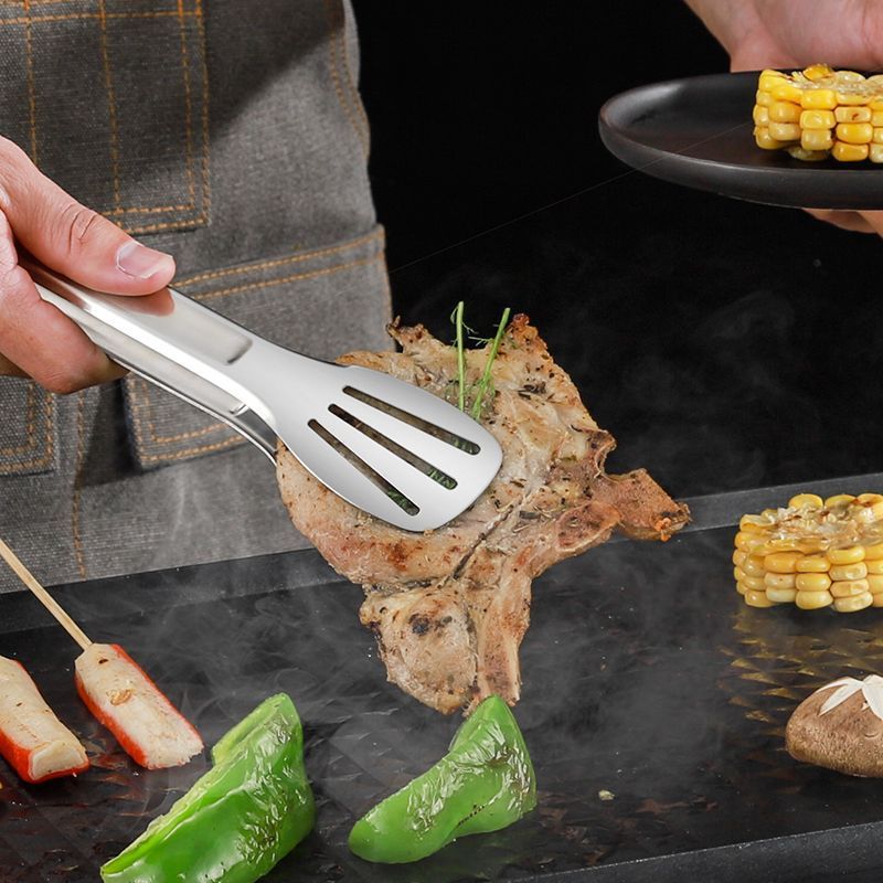 ステンレスの食品は台所の焼肉を挟んでステーキを焼きます。|undefined