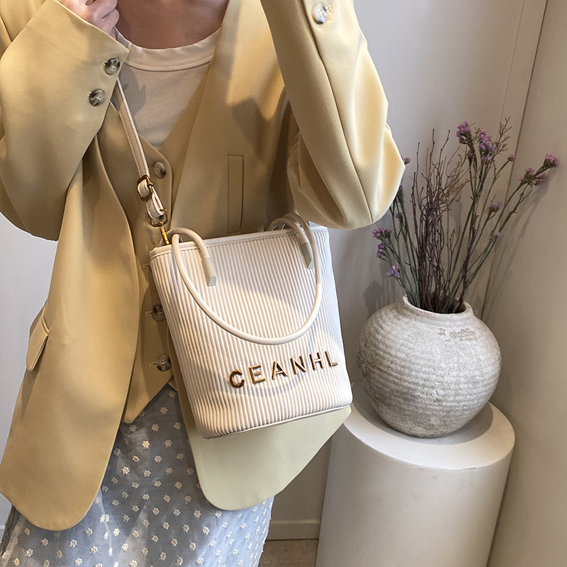 2025 otoño y invierno nuevo pequeño bolso a rayas de viento fragante bolso de cubo simple bolso de hombro de tendencia de mujeres bolso de mochila popular