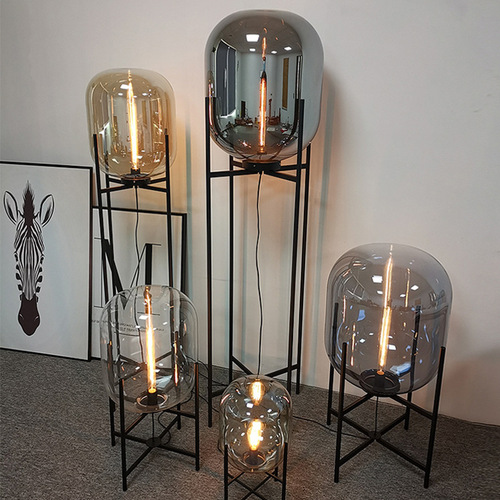 Postmodern Nordic industrial style smoke gray glass four-legged floor lamp with creative and personalized design for living room and bedroom.