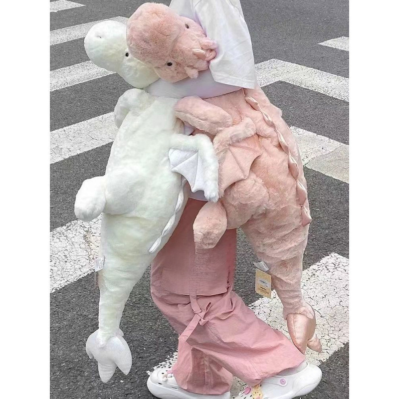 かわいい人形の小飛龍が寝ています。枕を抱いて恐竜のぬいぐるみを抱いて寝ます。|undefined