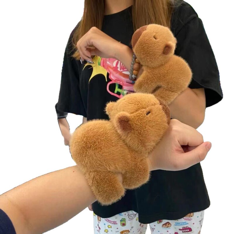 震える音の同じタイプのカピバラはパチパチと腹ばいになって腕のぬいぐるみを抱いています。|undefined