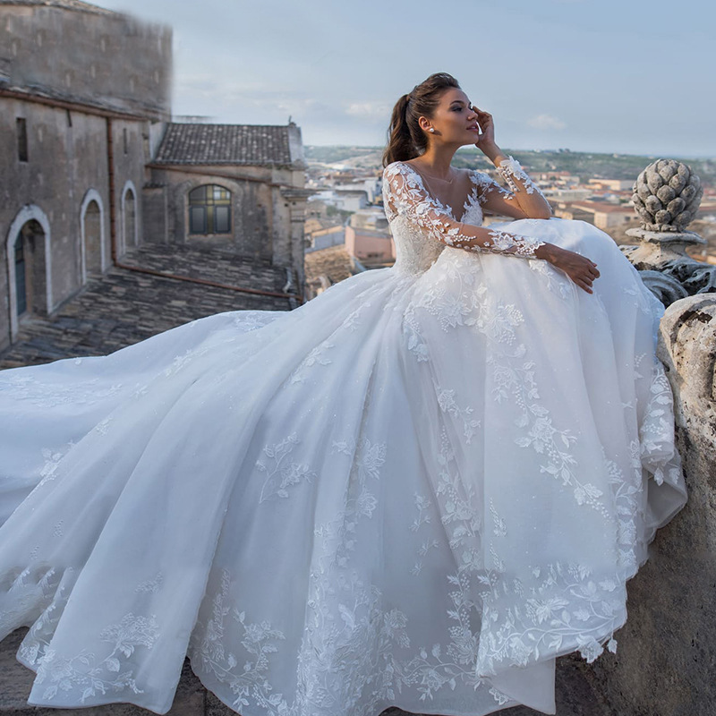 Vestido de novia para novias europeas y americanas, nuevo estilo 2026 con cola larga, vestido vintage sexy con cuello en V transparente, manga larga, estilo extranjero, para comercio internacional.