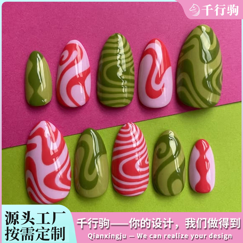 Custom 30-piece wearable nail art set in retro psychedelic red, green, and pink with contrasting swirl patterns and almond-shaped tips