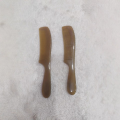 ショートヘアの長い柄の男性の髪を櫛にして、牛の角の櫛を整えます。