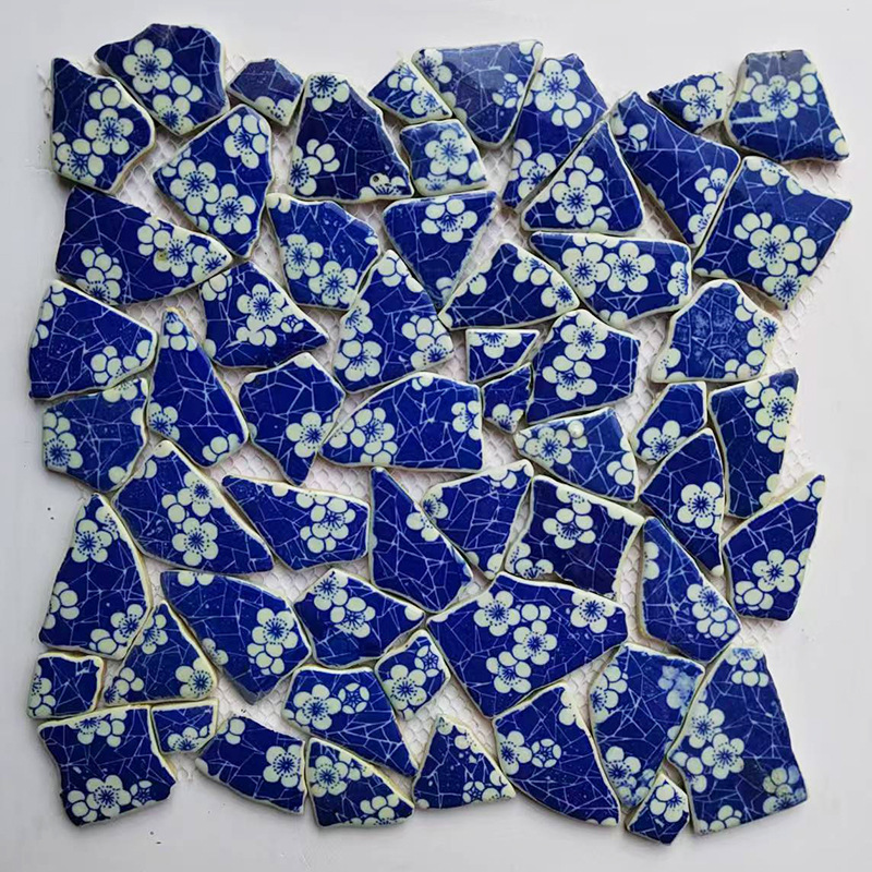 青と花の磁器の切れの陶磁器の破片はモザイクの不規則な背景の壁の屋外の装飾の壁のれんがをつづり合わせます。|undefined