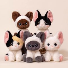 かわいい三花の猫のぬいぐるみのぬいぐるみの子供のテーブルは人形のベッドの上で寝ます。