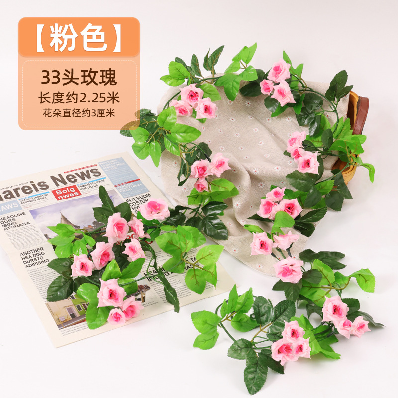 Simulación de flores falsas rosas de caña colgando la pared tubería de drenaje envuelta hoja verde que cubre la parte superior de la decoración de boda de plástico