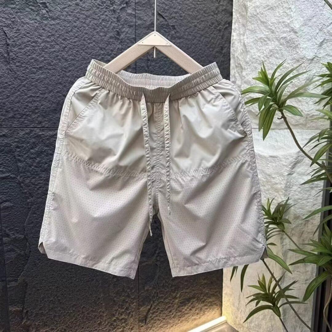 Verano nuevo estilo de secado rápido suelto tendencia casual perforado pantalones de cinco puntos moda masculina pantalones deportivos fríos y transpirables