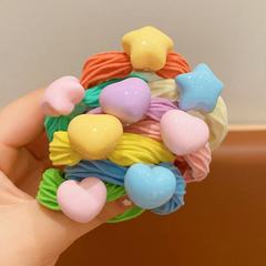 子供のキャンディー色のタオルリングの女の子はポニーテールの団子の髪のひもを刺します。
