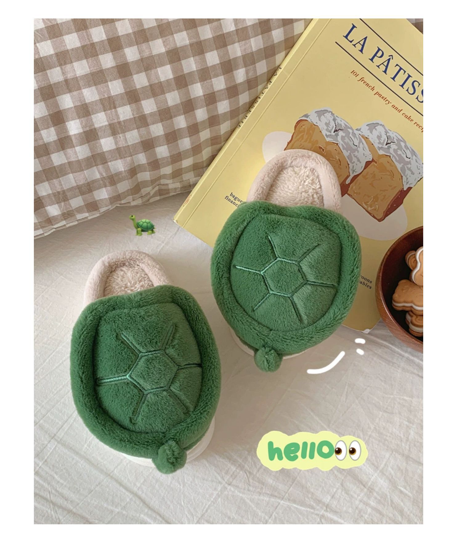 Green turtle-shaped slippers on a light surface with a book in the background.