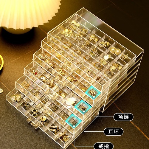 A transparent jewelry box with compartments for earrings, necklaces, rings, and beads