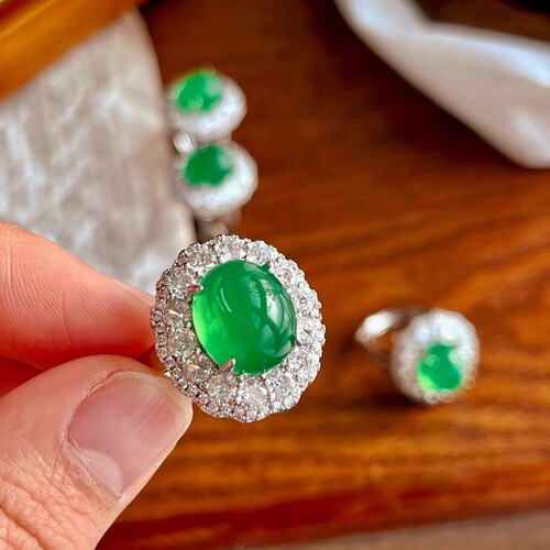 A natural light green jadeite egg face ring with a large, eye-catching green emerald, resembling jadeite, for women.
