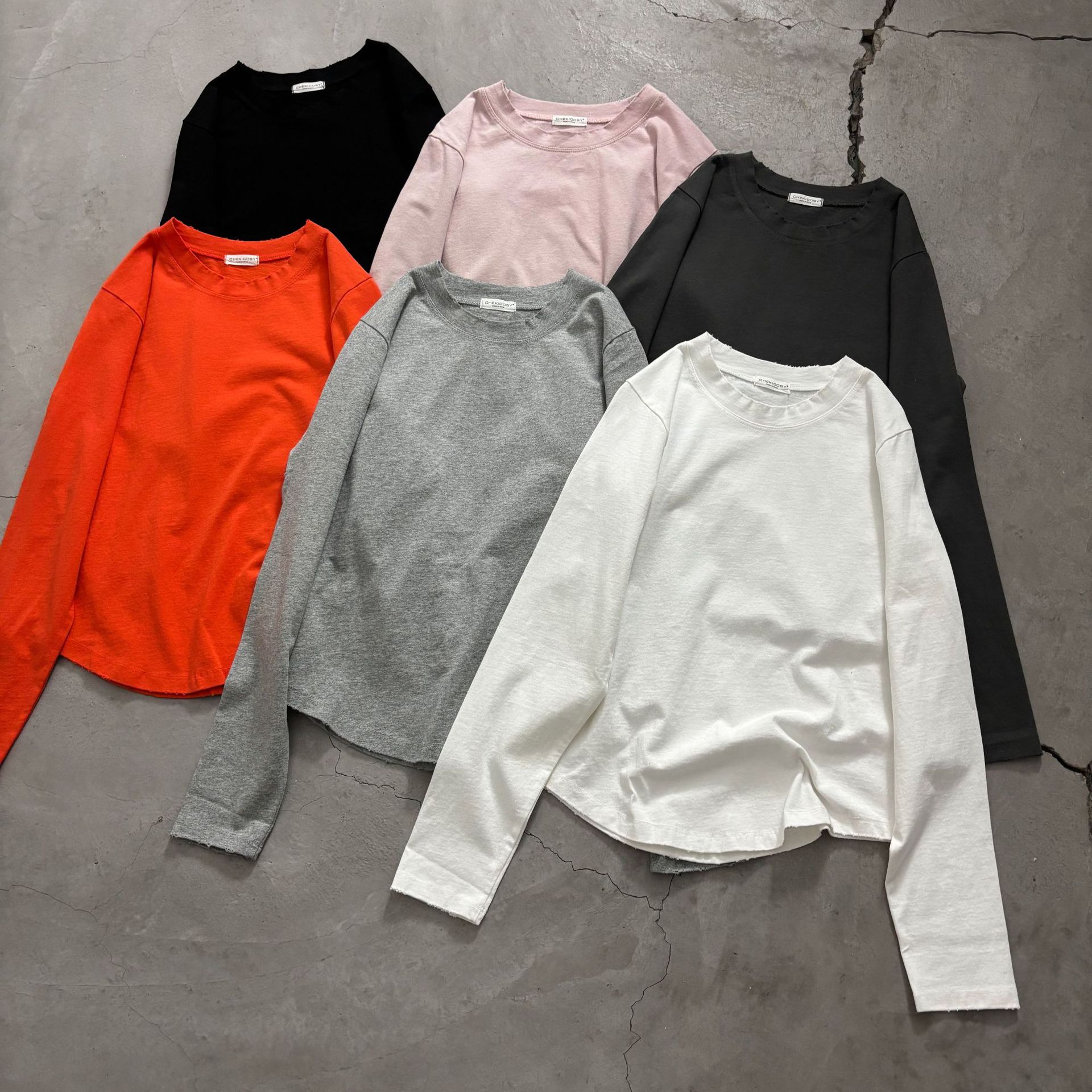 Dongdaemun long-sleeved cotton T-shirt with frayed edges and a relaxed, curved hem; a versatile basic inner layer.