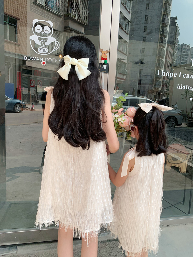 Mother and daughter in matching white dresses with fringe details