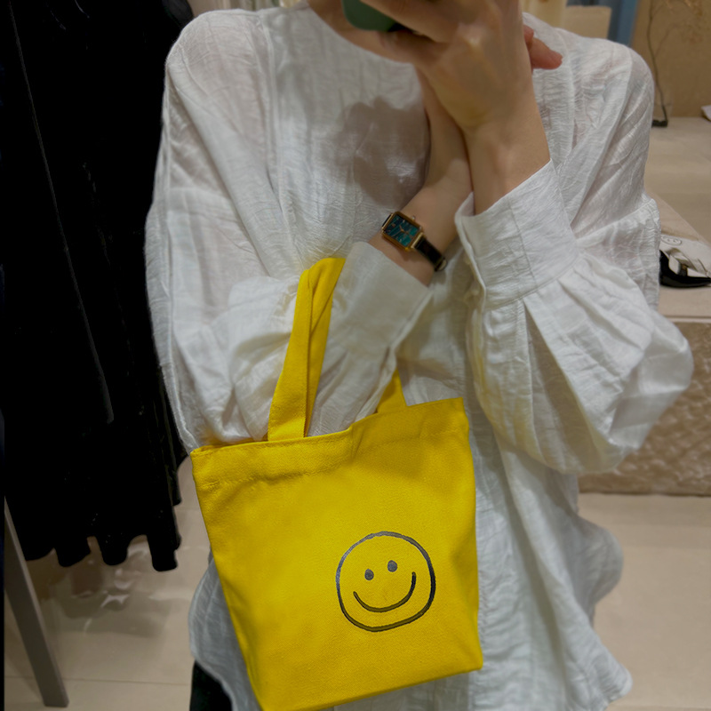 캔버스 가방 여성의 2023 새로운 휴대용 웃는 가방 캐주얼 대학 스타일 학생 작업 올 매치