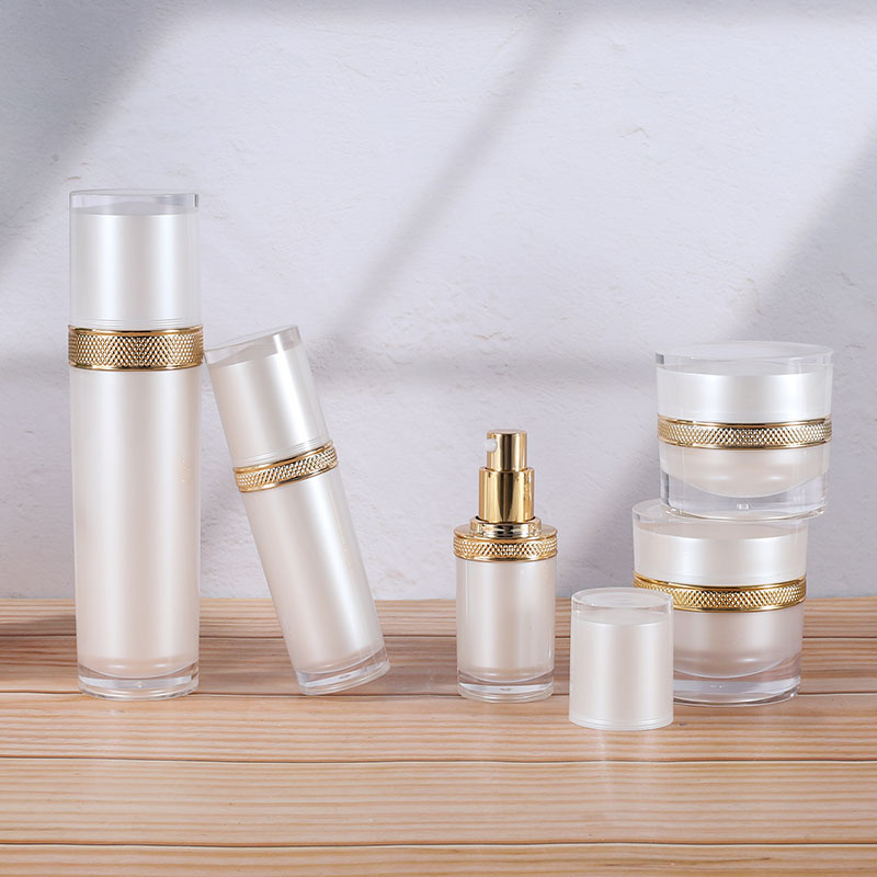 Botella acrílica blanca perlada para crema o loción, diseño con tapa dorada tipo diamante, recargable y elegante.