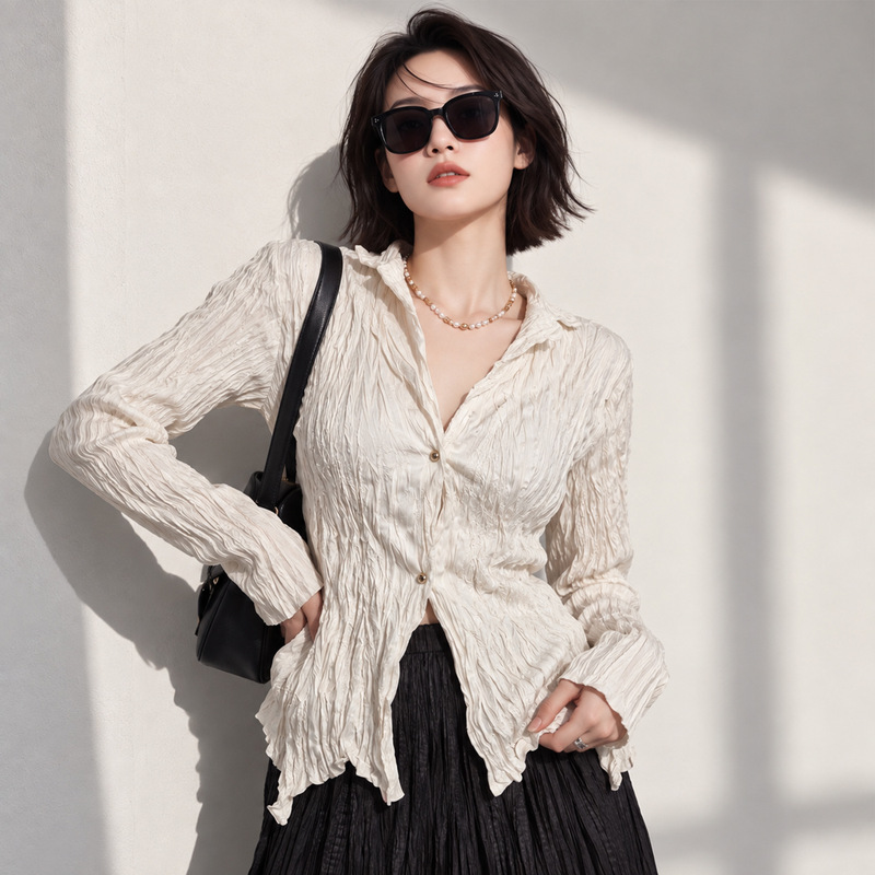 French-style textured pleated shirt with a collar, a new spring/autumn design for women, featuring a fitted waist, an asymmetrical hem, and long sleeves, creating an elegant look French-style textured pleated shirt with a collar, a new spring/autumn design for women, featuring a fitted waist, an asymmetrical hem, and long sleeves, creating an elegant look