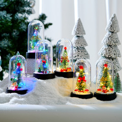 新しいクリスマスの夜の明かりのガラスカバーが光るクリスマスツリーのプラスチックカバーのテーブルの上に小さなプレゼントのクリスマスプレゼントを飾る
