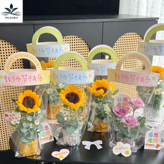 教師の日のヒマワリの花束の手は袋の花の手提げ袋のネットの赤い透明なopp袋の単一の花の包装の贈り物を持ちます。
