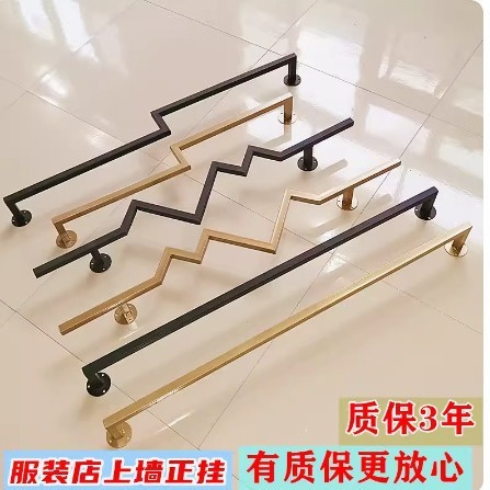 Display racks for women's clothing stores, wall-mounted hangers in black and gold, horizontal bars on the wall with clothes hanging on the rods