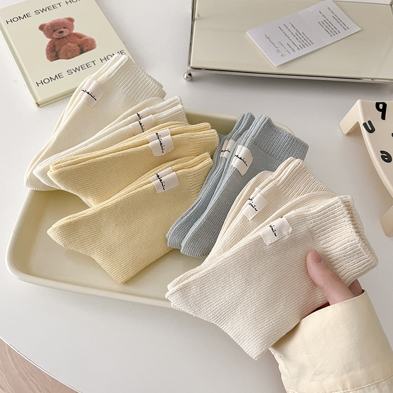 Otoño e invierno Nuevos calcetines de algodón absorbentes de sudor calcetines de pila serie de crema para mujer estilo ins Corea del Sur etiqueta de tela calcetines de media pantorrilla moda