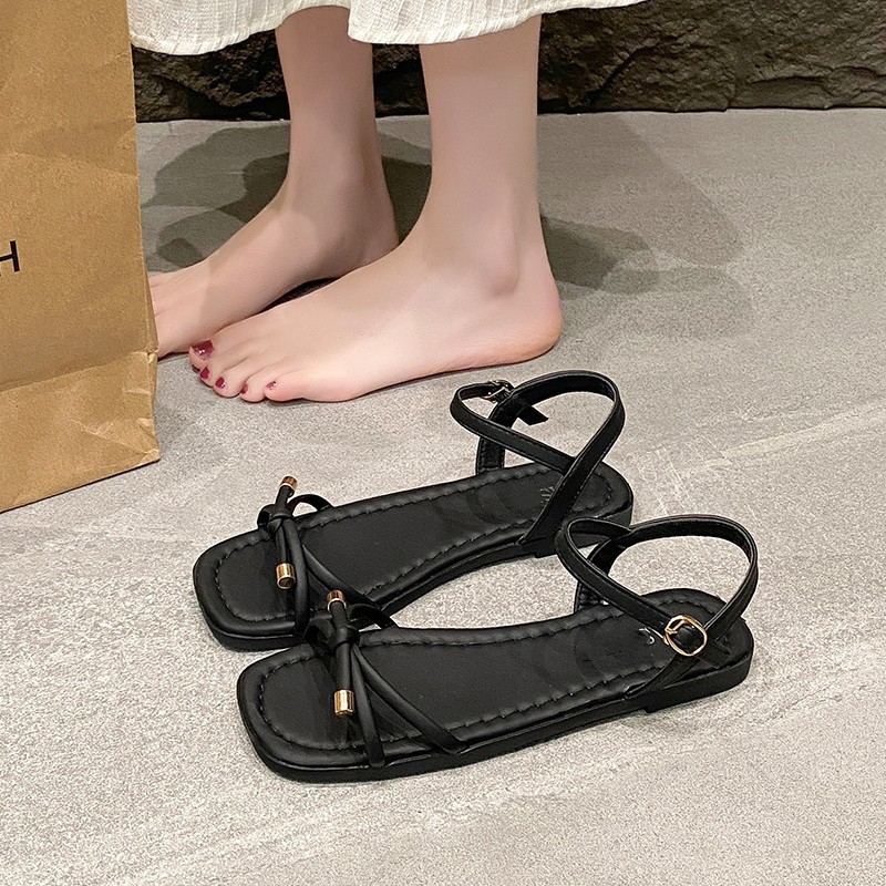 Arco sandalias planas para mujeres verano 2026 nuevo estilo con una sola línea suave de hadas estilo versátil no cansado zapatos de viaje