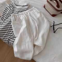 小柄な背の高い白い亜麻のワイドパンツの女性の秋のモデルはやせて柔らかい感じがします。
