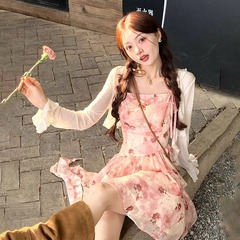 海辺の休暇には、砕花ストラップの不規則なワンピースとニットカーディガンのストールを着ている女子学生
