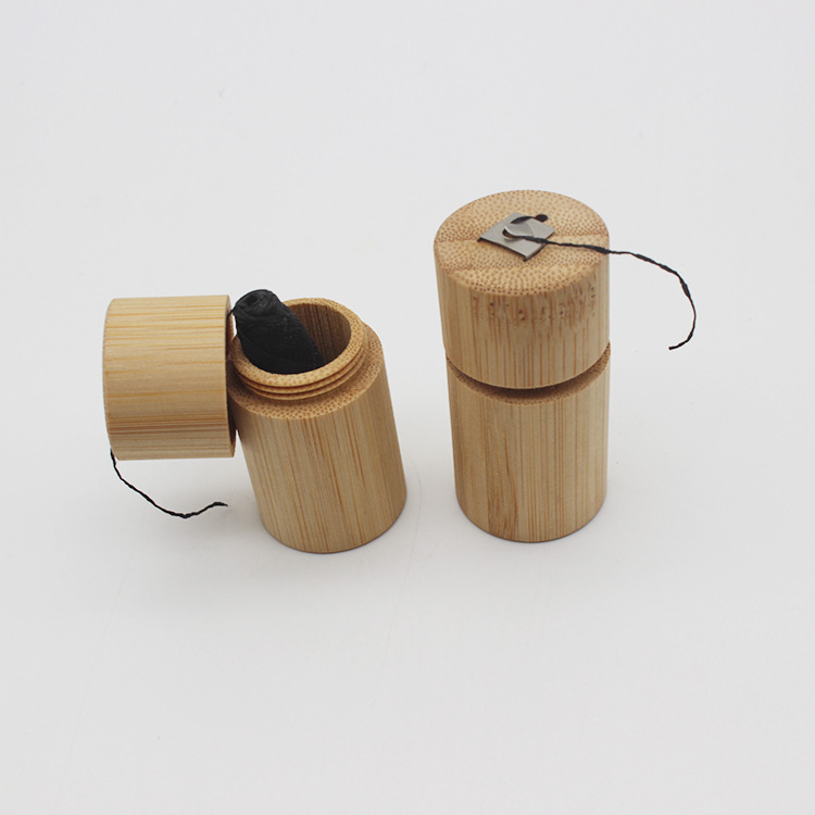 Light brown bamboo toothpick holder with a black string and metal clip featured in a portable biodegradable case for bamboo floss tube.